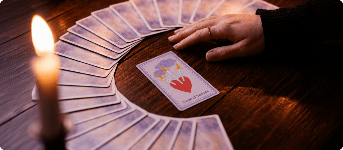 Tarot cards fanned out on a wooden table beside a lit candle